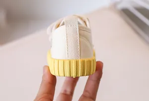 Close-up of kids canvas shoe showing the durable yellow rubber sole and heel pull tab