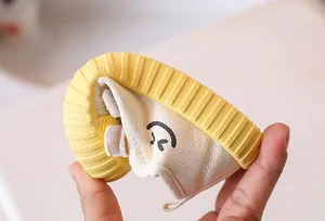 Close-up of flexible rubber sole and cute smiley embroidery on children canvas shoe
