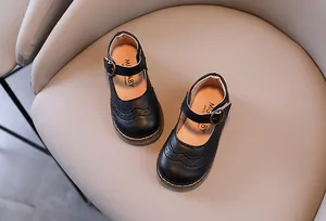 Close-up of black Mary Jane shoes for girls with elegant brogue carving and metal buckle