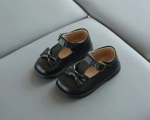 Détail de chaussures Mary Jane noires pour filles avec bride en T et nœud sur texture
