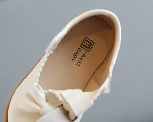 Détail de la chaussure de princesse blanc cassé pour fille avec nœud et logo de marque