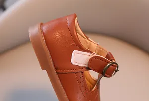 Gros plan détaillé des chaussures Mary Jane en cuir marron pour filles avec motif ajouré