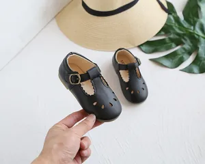 Detail shot of black girls' hollow-out T-strap Mary Janes with retro metal buckle design