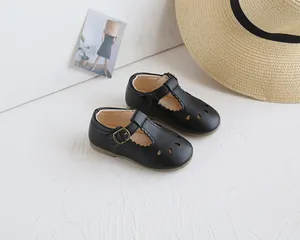 Detail of black T-strap Mary Jane shoes with hollow carvings and vintage buckle