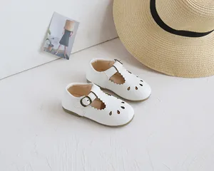 Detail of cream white leather kids shoes featuring T-strap and laser cut hollow pattern