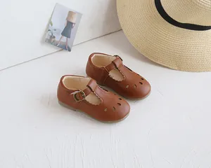 Detail of brown Mary Jane shoes for girls with droplet cutouts and T-strap buckle closure