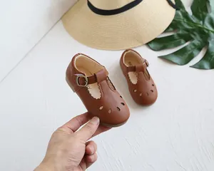 Detail view of brown Mary Jane shoes with hollow cut-outs and scalloped edge trim