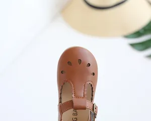 Detail of brown Mary Jane shoes featuring teardrop cutouts and retro metallic buckle