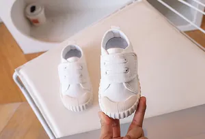 Detail of white canvas kids sneakers with velcro strap and rubber toe cap