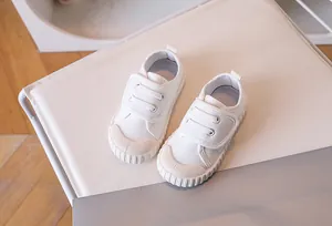 White canvas toddler shoe with double Velcro straps and durable rubber toe cap protection
