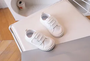 Detail of white canvas toddler shoes with velcro straps and rubber toe cap design