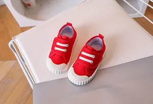Detail of red canvas kids shoes with rubber toe cap and blue striped lining