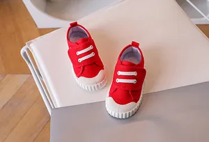 Detail of red kids canvas sneakers with velcro straps and white rubber toe caps