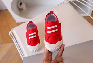 Detail of red kids canvas shoe with velcro strap and protective rubber toe cap