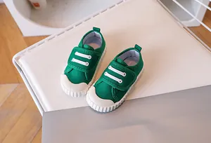 Detail of green canvas kids shoe with white rubber toe cap and velcro strap closure