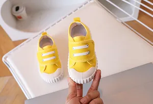 Detail view of yellow canvas kids sneakers with durable rubber toe and velcro closure