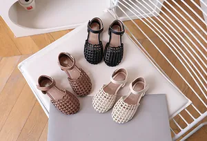 Close-up of woven girls' sandals in black, brown and beige with velcro straps