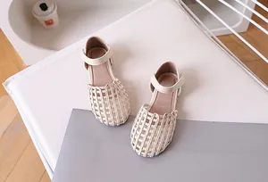 Detailed view of beige woven girls sandals featuring stylish cross-knit hollow design and ankle strap
