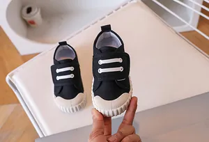 Detail of children's black canvas shoes with velcro straps and white rubber toe caps