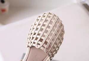Detailed macro shot of girls woven beige leather sandals with hollow out grid toe
