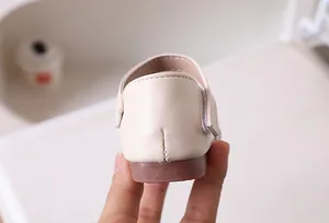 Detail of cream girls' sandals featuring reinforced back heel stitching and brown rubber sole