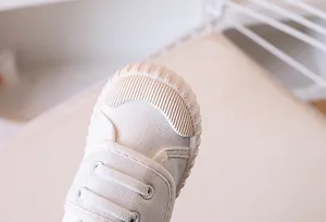 Macro detail of the white canvas fabric and reinforced rubber toe cap on children shoes