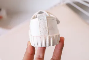Detail showing white canvas kid shoe with heel pull tab and non-slip rubber sole