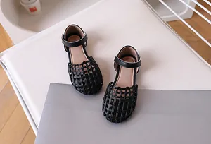 Close-up of black woven leather cage design and ankle buckle strap on kids sandals