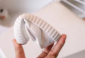 Detail of highly flexible rubber sole for white kids canvas shoes showing elasticity