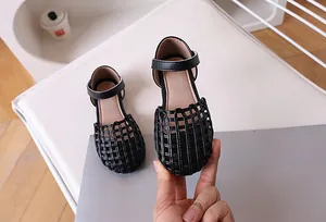 Detail view of girls black woven sandals with velcro strap and closed toe design
