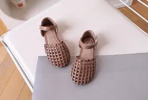 Close-up of brown woven leather sandals for girls with velcro straps and hollow cage design