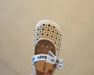 Macro-opname van beige kinderschoenen met uitgesneden bloemmotief en decoratieve strik