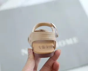 Detailed view of the adjustable metal buckle and soft heel strap on girls' sandals