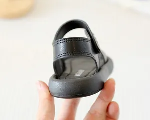 Détail de sandales noires pour enfants avec doubles coutures et semelles souples