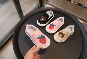 Détail de chaussures en toile pour enfants avec broderie ours et bandes élastiques