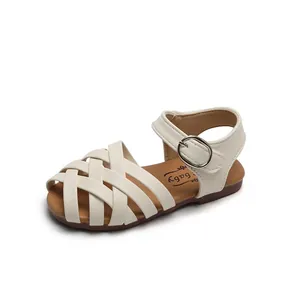 Girls woven cross strap sandals in beige with soft brown soles and buckle closure