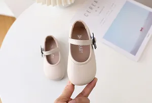 Detailansicht beige Baby-Mary-Janes aus mattem Leder mit einer hübschen schwarzen Schleife