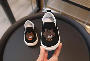 Détail des chaussures en toile pour enfants avec broderie ours mignon et style slip-on
