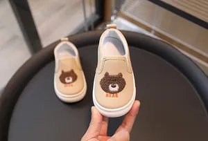 Gros plan d'une chaussure en toile pour enfant avec broderie ours et bande élastique
