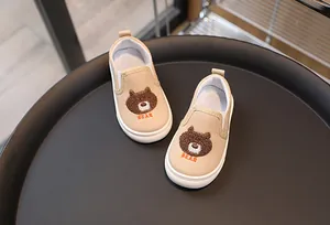 Gros plan de chaussures en toile kaki pour enfants avec broderie d'ours et semelle en gomme