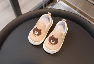Détail de la chaussure en toile beige avec ours en peluche et broderie pour enfants
