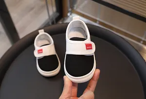 Close-up of baby canvas shoe featuring wide velcro strap and red woven label detail