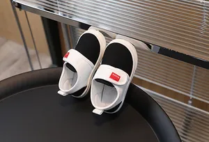 Detail of kids canvas shoes with black fabric, white rubber toe, and velcro strap closure