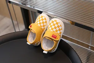 Detail of yellow checkerboard kids canvas sneakers with velcro strap on modern tray