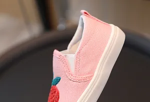 Détail de chaussures en toile rose pour enfants avec broderie fraise et design élastique