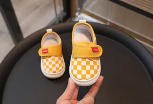 Close-up of yellow checkered canvas toddler shoes with velcro strap and rubber sole