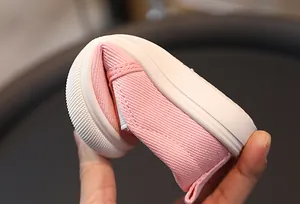 Gros plan d'une chaussure bébé en toile rose pliable montrant la souplesse de la semelle