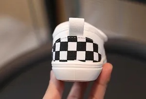 Detail view of children canvas shoes featuring classic checkerboard pattern heel and rubber sole