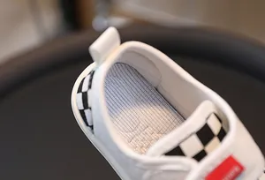 Detailed macro view of children canvas shoes featuring checkered ribbon and padded heel
