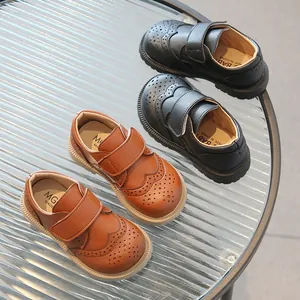 Zwarte en bruine kinder brogue lederen schoenen met klittenbandsluiting op tafel
